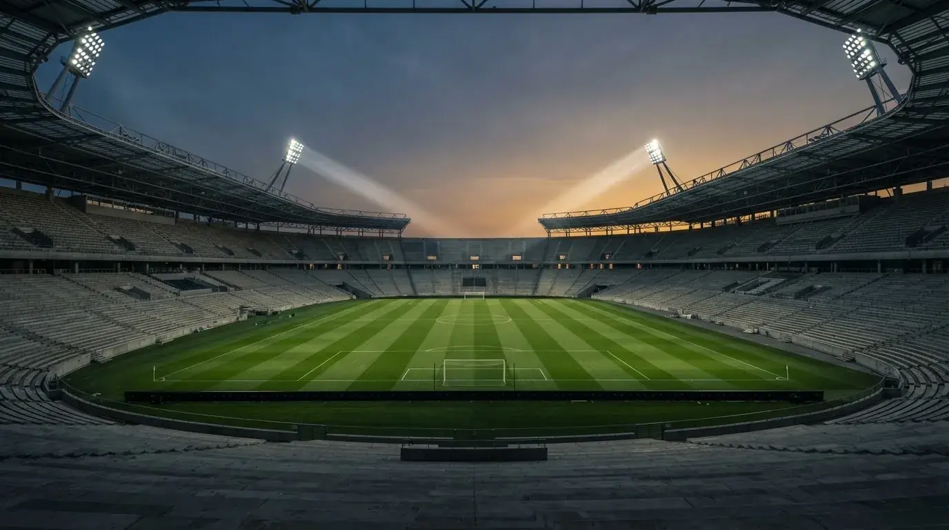 Een leeg voetbalstadion met lichtmasten bij schemering
