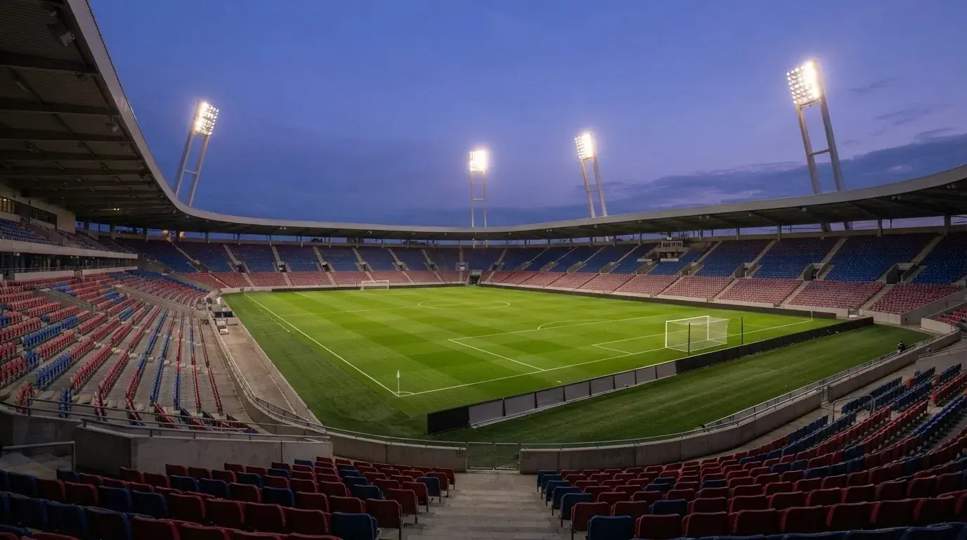 Een leeg voetbalstadion met lichtmasten bij schemering