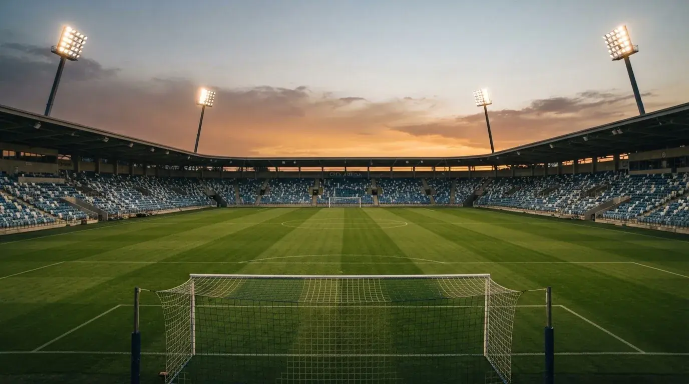 Een leeg voetbalstadion met lichtmasten bij schemering