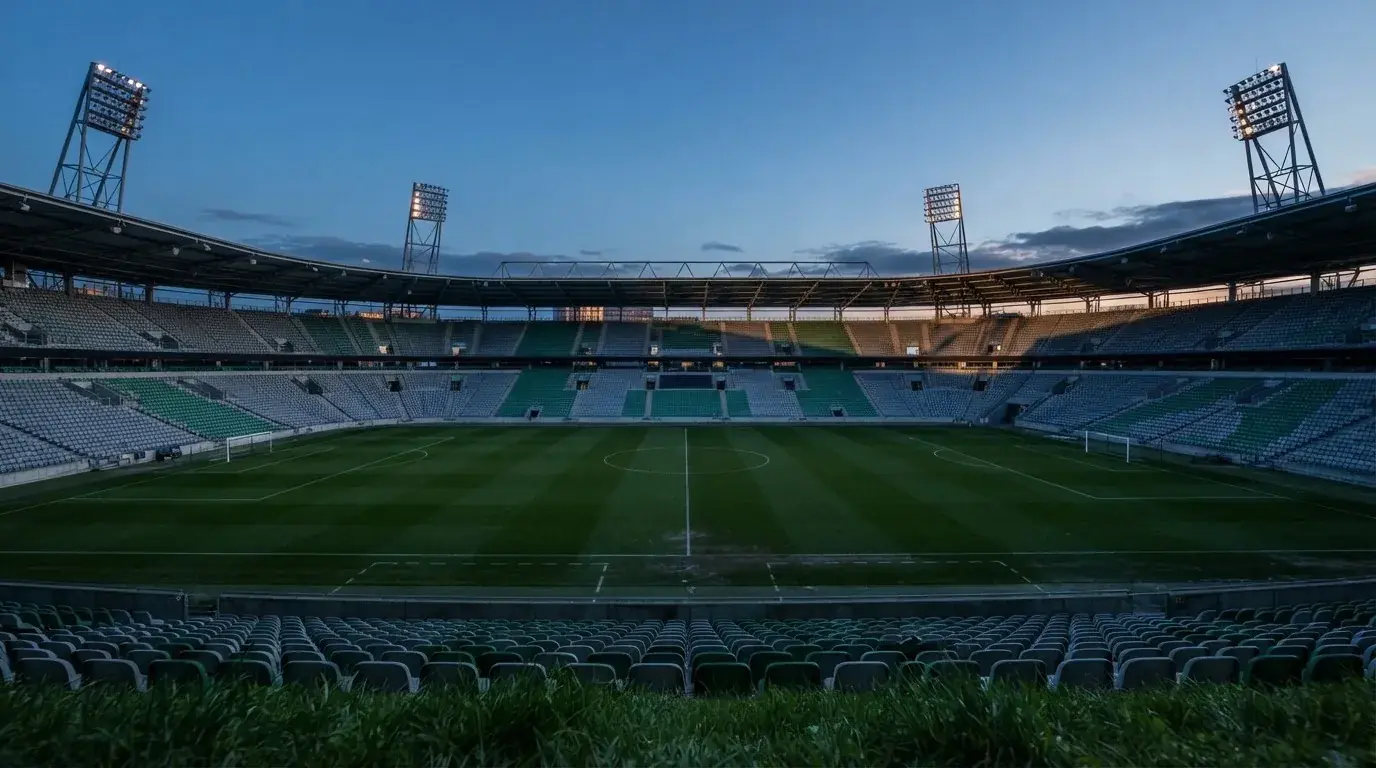 Een leeg voetbalstadion met lichtmasten bij schemering