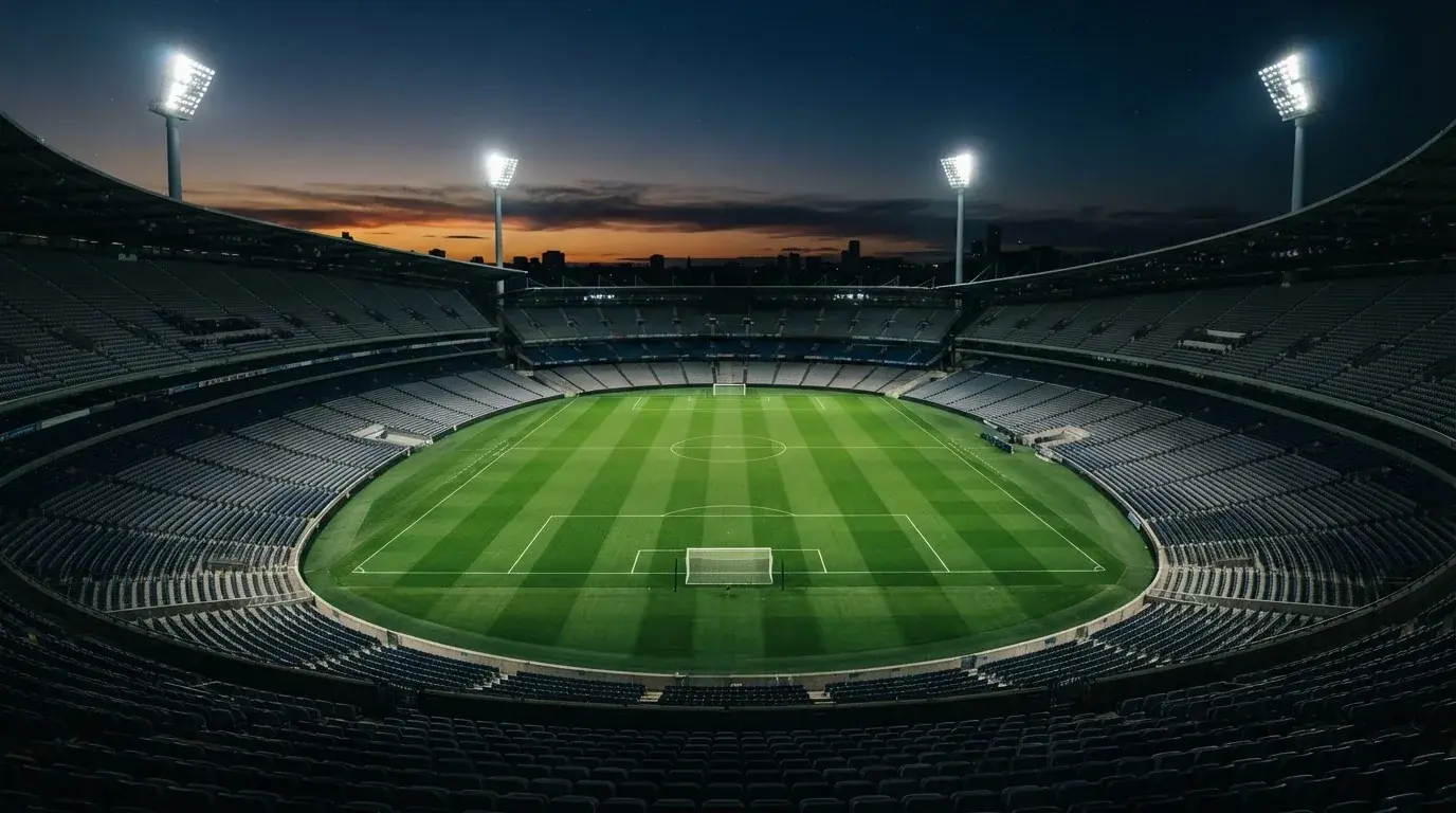 Een leeg voetbalstadion met lichtmasten bij schemering
