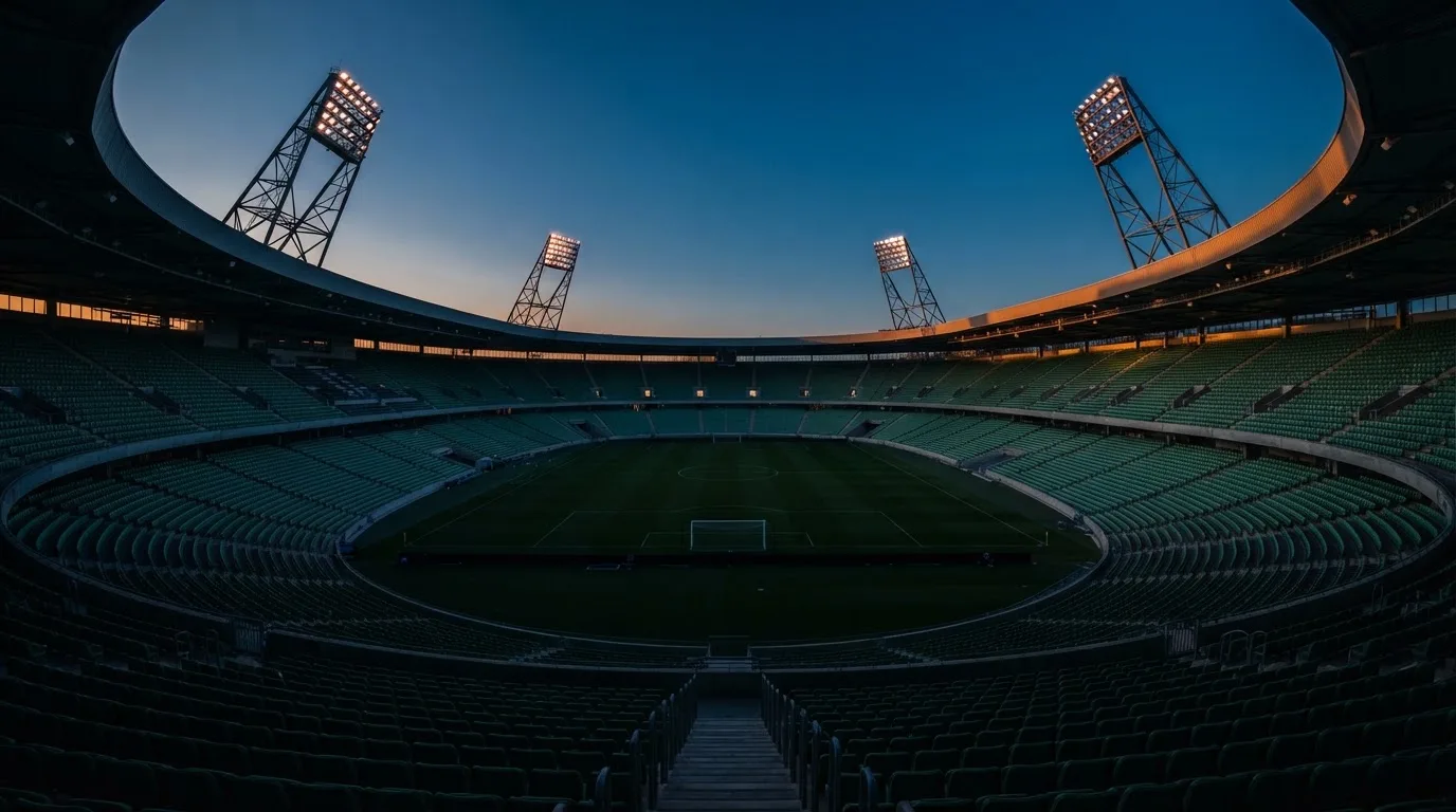 Een leeg voetbalstadion met lichtmasten bij schemering