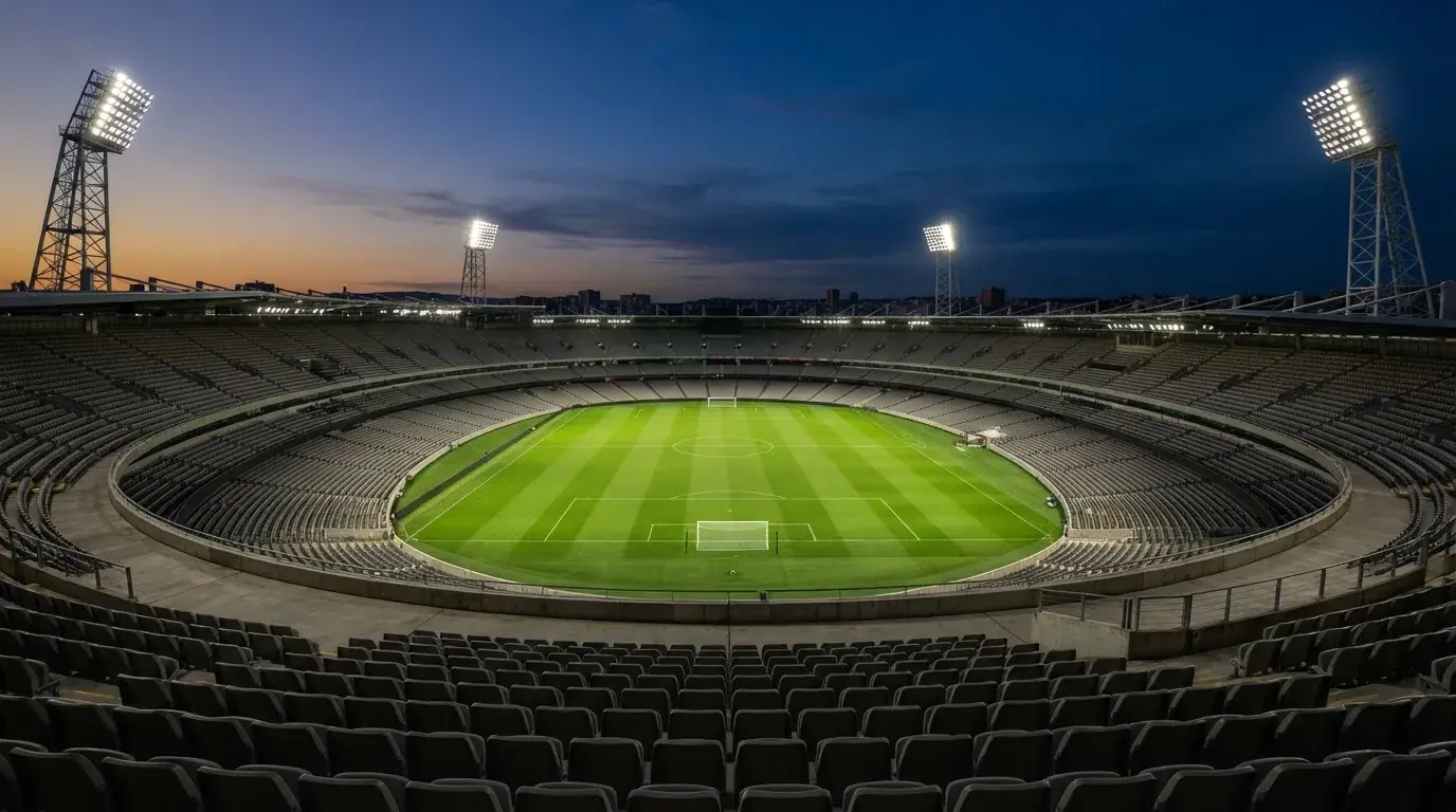 Een leeg voetbalstadion met lichtmasten bij schemering