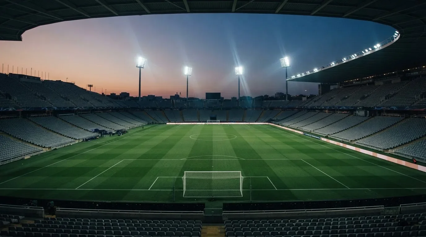 Een leeg voetbalstadion met lichtmasten bij schemering