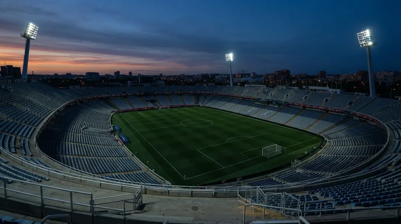 Een leeg voetbalstadion met lichtmasten bij schemering